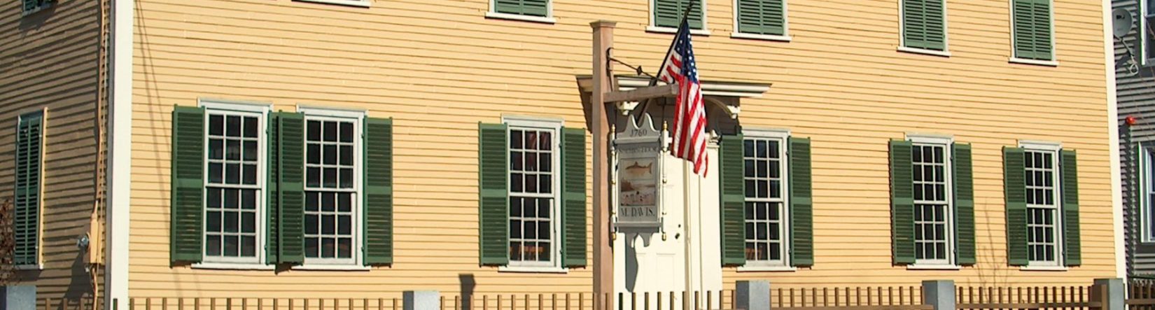 spalding house, historic yellow house with dark green shutters, an American flag and sign hanging