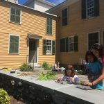 families use leaves, flowers and natural items to make fairy gardens on the patio behind the spalding house, mustard yellow house with dark green shutters