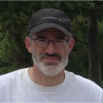 David Braslau, man in hat smiling with trees behind