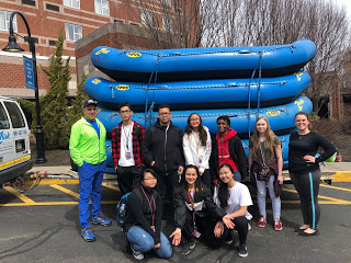 high school students and staff pose by rafting boats in parking lot of hotel