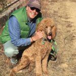 Stephen Conant posing with a tan poodle