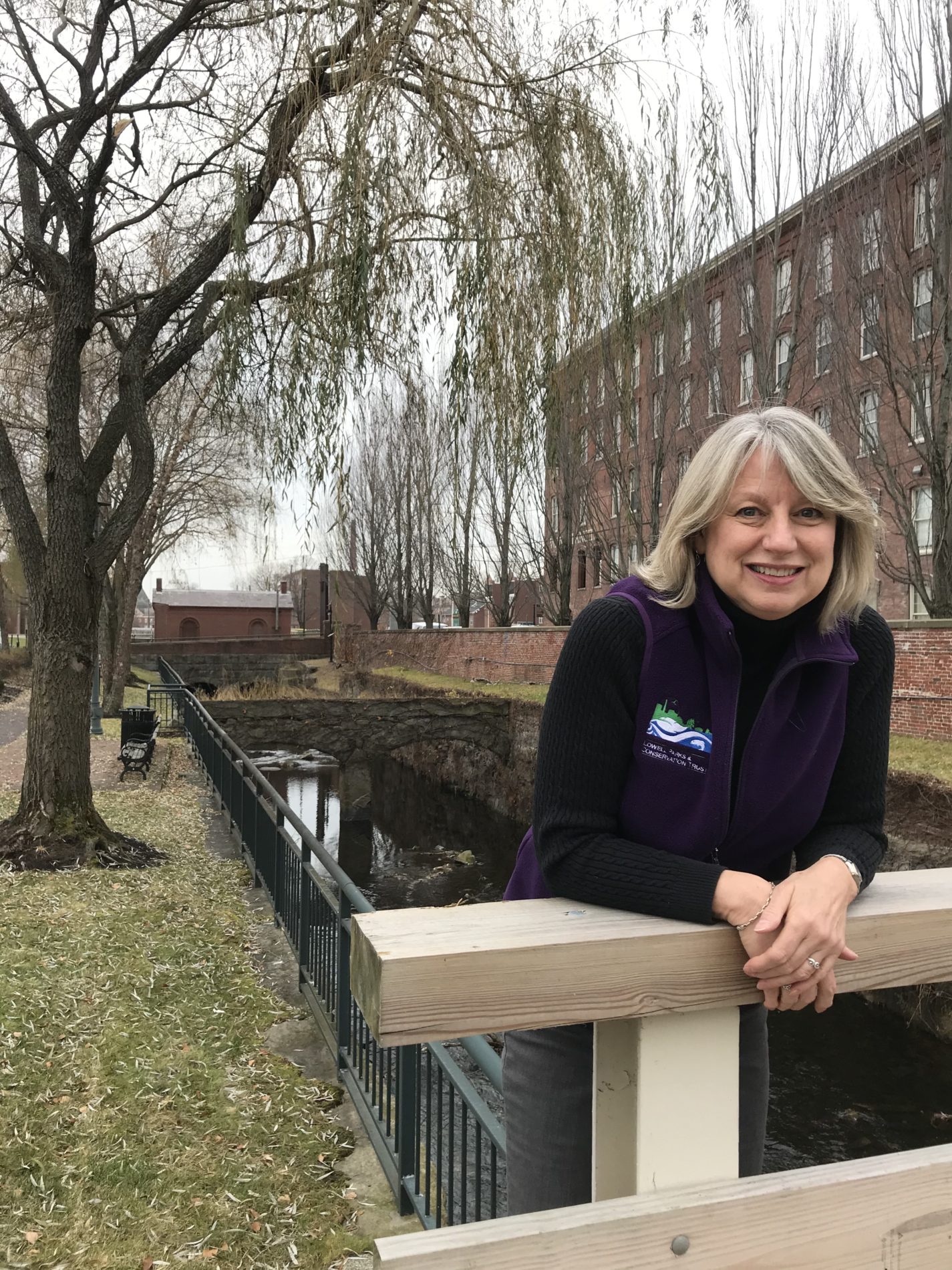Sheila Kirschbaum LP&CT president smiling by a Lowell canal and willow tree