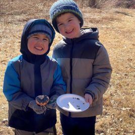 Two brothers hold up homemade bird feeders