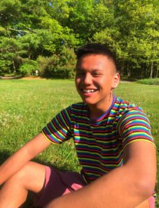 darren, a high school student smiling sitting on grass in sunshine