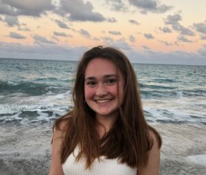 abby, a high shcool student smiling with ocean and pink sky background