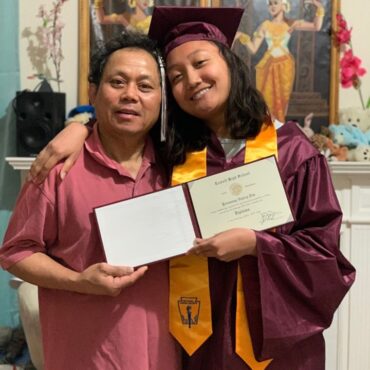 graduating high school student with father showing her diploma