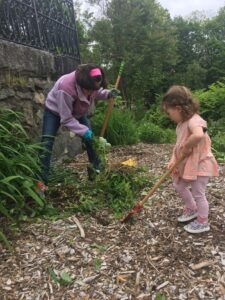 mother and young girl rake mulch and pull weeds