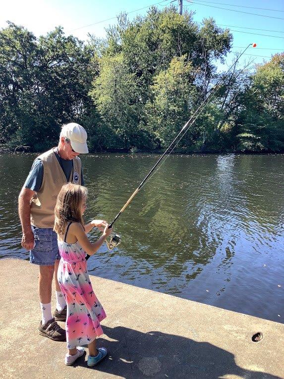 staff teaches girl to fish at family outdoors day